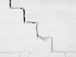 Fissure en escalier suivant les joints de maçonnerie d'un mur en parpaings