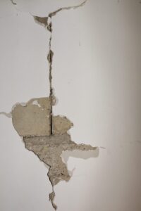 Fissure structurelle traversante sur un mur porteur, béton apparent